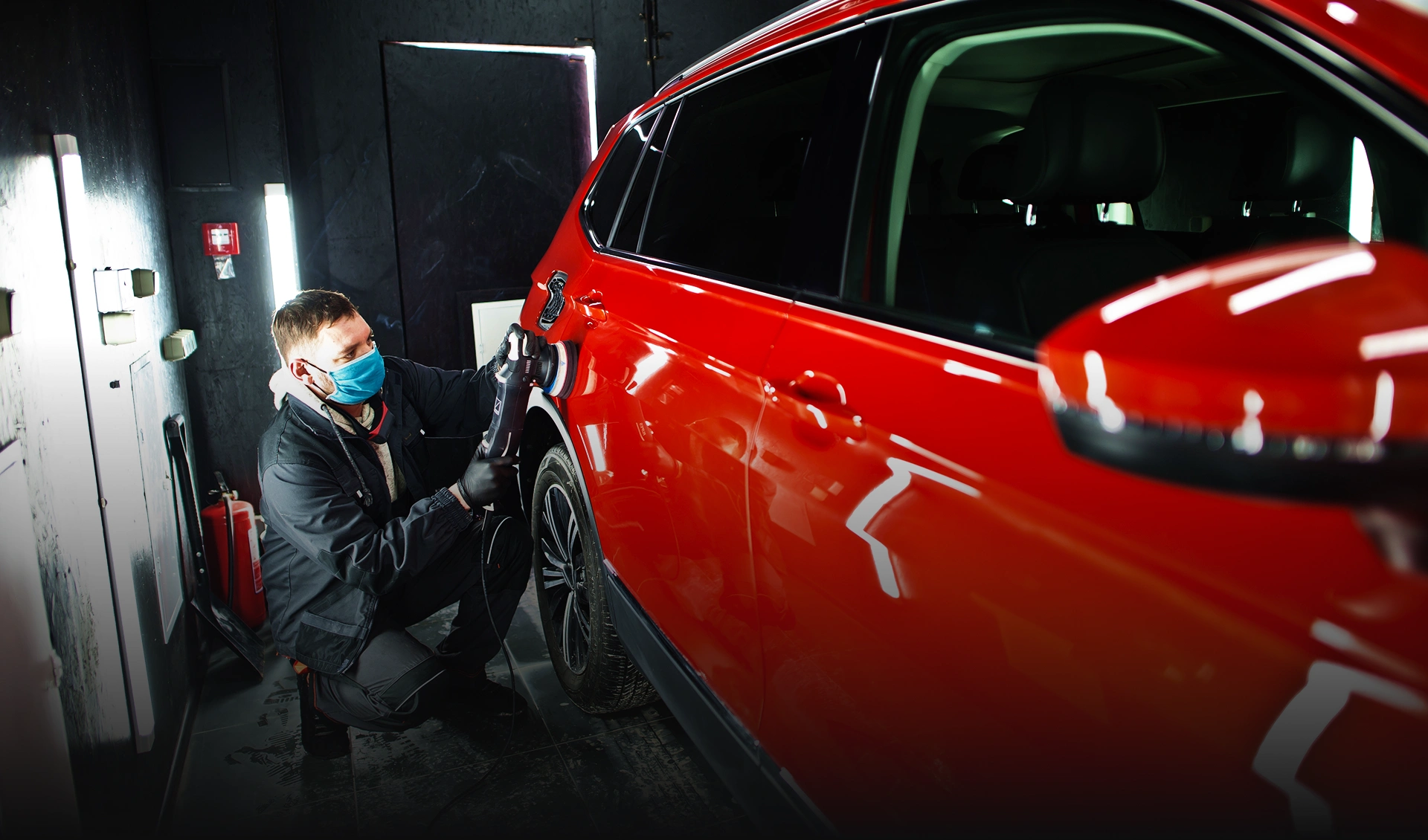car-detailing-concept-man-face-mask-with-orbital-polisher-repair-shop-polishing-orange-suv-car